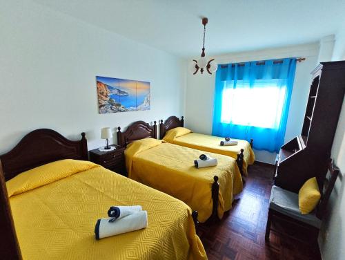 two beds in a room with yellow sheets at Pacheco's Guesthouse in Lagos