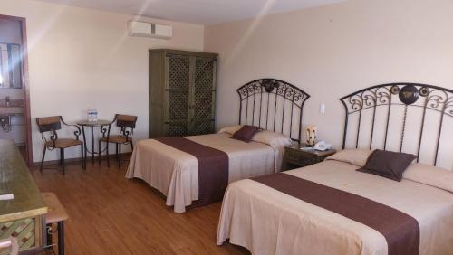 a hotel room with two beds and a table at HOTEL PLAZA PACHUCA in Zapotlán de Juárez