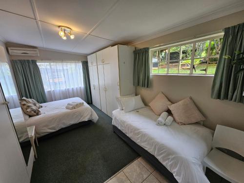 a small room with two beds and a window at Leopards Tree Garden Cottage in Greytown