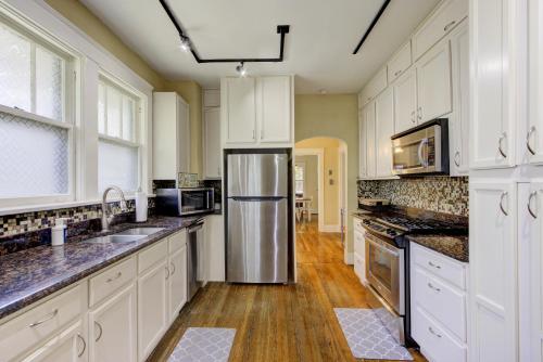 a kitchen with white cabinets and a stainless steel refrigerator at Beautiful Bungalow Stones throw from Cooper Young in Memphis