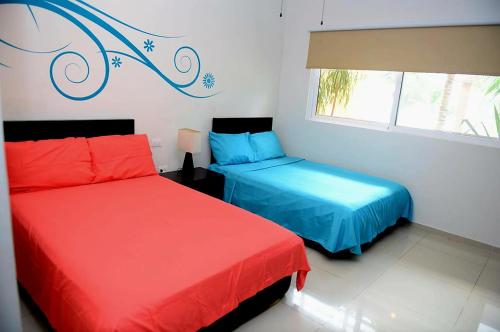 zwei Betten in einem Zimmer mit roten und blauen in der Unterkunft Oasis del Sol in Playa del Carmen