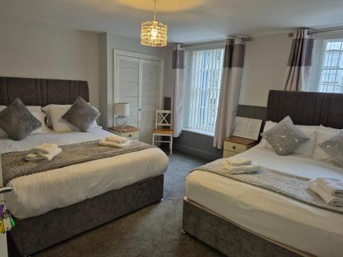 a bedroom with two beds and a chandelier at The Royal Oak Pub in Lampeter