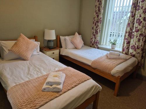 a room with two beds with a window and a table at The Royal Oak Pub in Lampeter