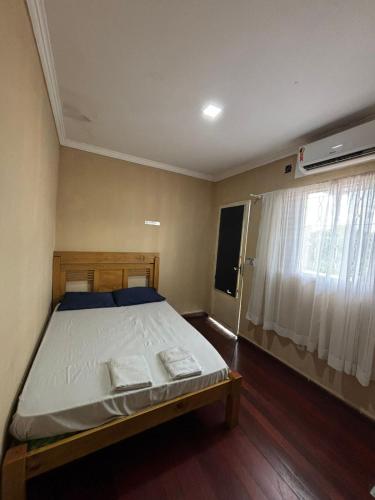 a bedroom with a bed and a window with white curtains at HOTEL TÊTÊ in Várzea Grande