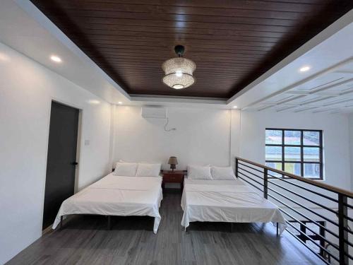 two beds in a room with a ceiling at The Guest House Zambales in Cabangan
