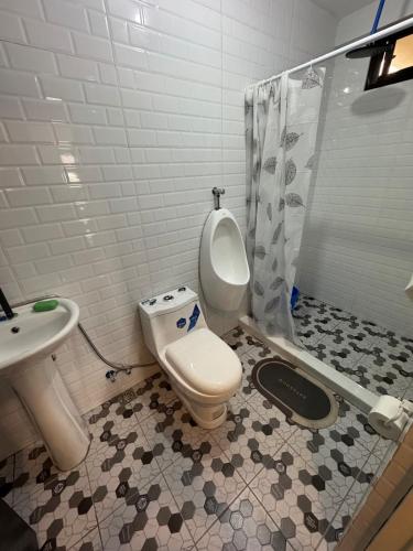 a bathroom with a toilet and a sink and a shower at The Guest House Zambales in Cabangan