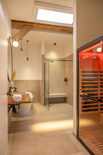a bathroom with a shower and a sink and a tub at Relax In A Thatched Barn With A Sauna in Ratekau