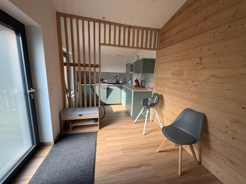 a room with a kitchen with a chair and a table at Le Chalet des 5 avec piscine vue sur les montagnes et en lisière de forêt in Lutzelhouse