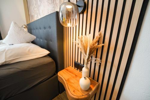 a table with a vase on it next to a bed at Hotel Berghof in Hellenthal