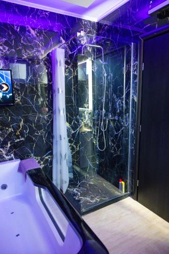 a bathroom with a tub with a marble wall at Foča Apartman STORY LUX in Foča