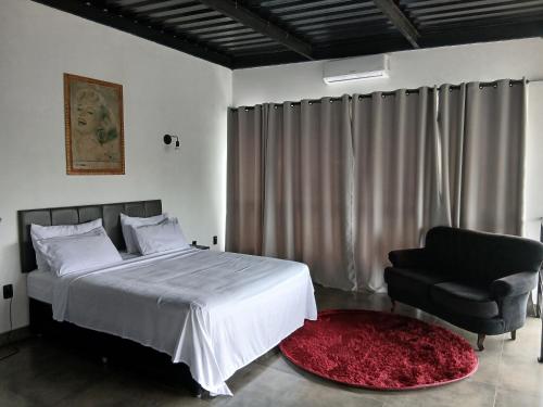 a bedroom with a bed and a black chair at Casa com piscina aquecida, estilosa e privativa in Nazaré Paulista