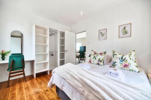 a white bedroom with a bed and a chair at Stylish, Private, Thoughtful, Spotless, Aircon, Parking in Hermanus