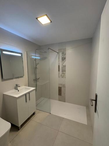 a white bathroom with a shower and a sink at La Casita de Kai in El Médano