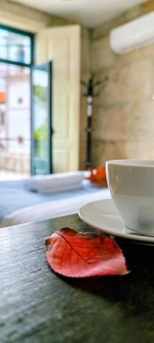 a coffee cup and a leaf on a table at Donna Nega Guest House in Caminha
