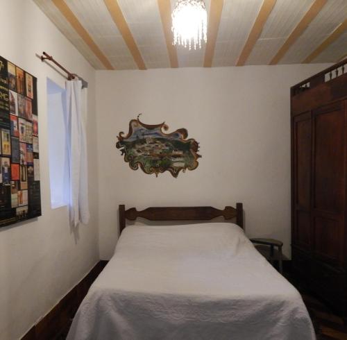 a bedroom with a bed and a chandelier on the wall at Pouso das Glicínias - B&B in Ouro Preto
