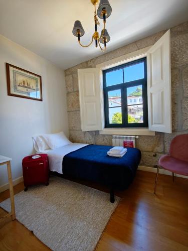 a bedroom with a bed and a window and a red suitcase at Donna Nega Guest House in Caminha