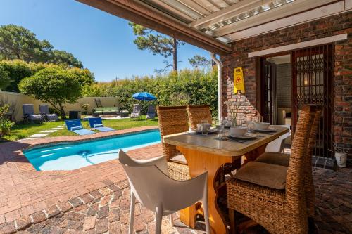 a patio with a table and chairs next to a pool at 3 Bedroom Family Home, Pool & Garden, Upper Constantia in Constantia