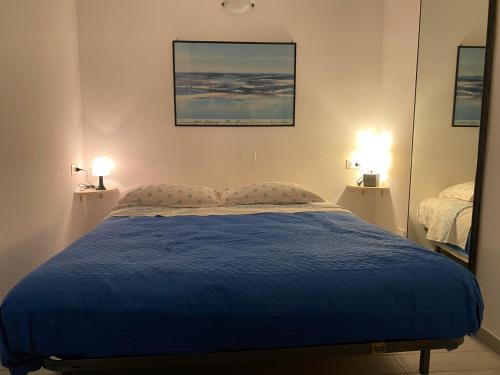 a bedroom with a blue bed and two lamps at Indy Sea Home in Lido degli Estensi