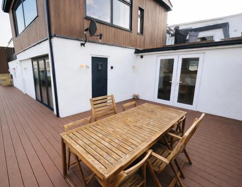 a wooden table and chairs on a deck at Fabulous Ground Floor Apt Adjacent to Beach in Rhosneigr