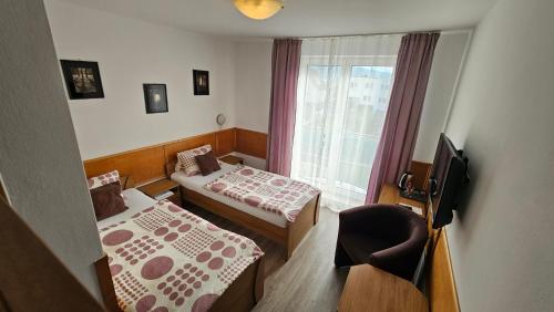 a room with two beds and a chair and a window at Penzión Magnólia in Trenčín