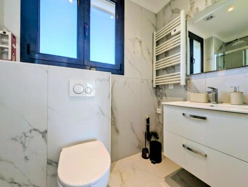 a white bathroom with a toilet and a sink at La Régalide 2A in Roquebrune-Cap-Martin