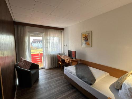 a hotel room with a bed and a chair and a desk at Hotel Hohe Wart in Herbrechtingen