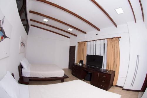a bedroom with a bed and a tv and a desk at Café de Playa Beach Front Hotel in Coco