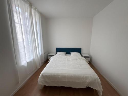 a white bed in a white room with two windows at Appartement Voltaire in Romilly-sur-Seine