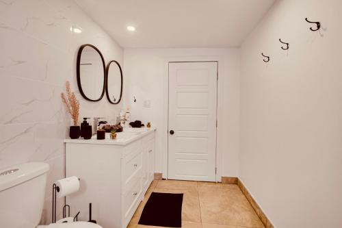 a white bathroom with a toilet and a mirror at Laurier Suites in Gatineau