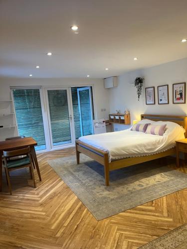 a bedroom with a bed and a desk and windows at The Summerhouse in Cheadle