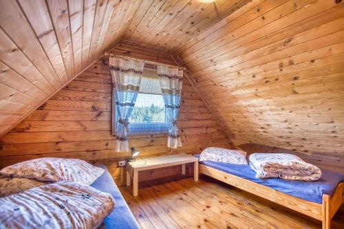 a bedroom with two beds in a log cabin at Domki u Henia i Anety in Werlas