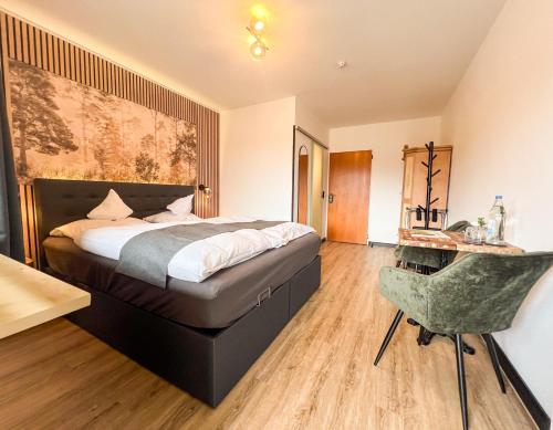 a bedroom with a bed and a chair in it at Hotel Berghof in Hellenthal