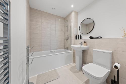 a white bathroom with a toilet and a tub and a sink at Luxury 2BR Staines 12 Mins to Heathrow & Thames in Staines