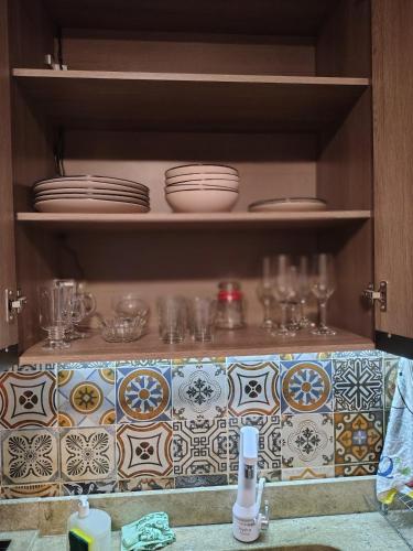 a kitchen cabinet with plates and glasses on shelves at Chico's House in Uruguaiana
