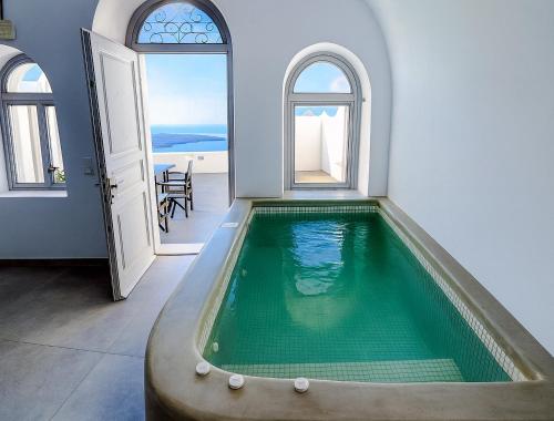 a swimming pool in a house with an open door at Yposkafo Suites - Villa - Santorini in Fira