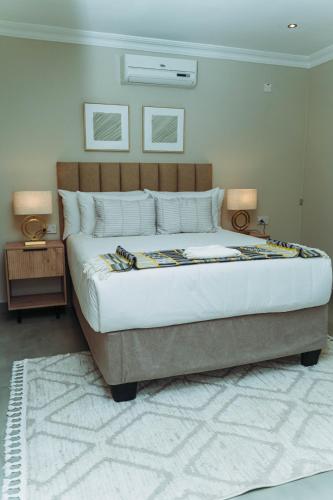 a bedroom with a large bed with two lamps on it at Tlou Luxe stay in Gaborone