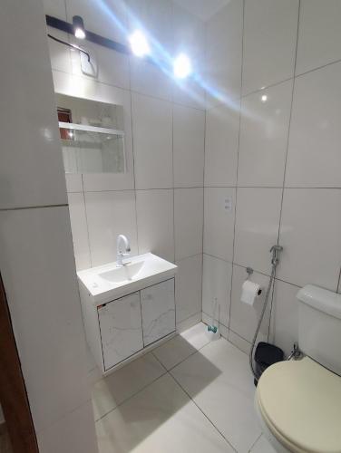 a white bathroom with a sink and a toilet at Microcasa com ar em Resende in Resende