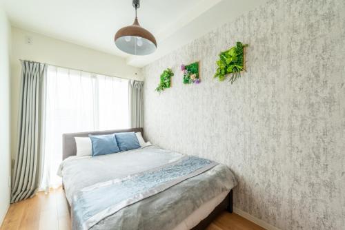 a bedroom with a bed and a wall with plants at The Peak Tengachaya 605 KIX Direct Cozy Elegance near Namba in Osaka