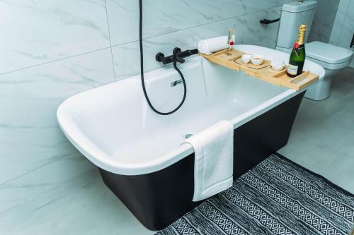 a bathroom with a bath tub with a bottle of champagne at Tlou Luxe stay in Gaborone