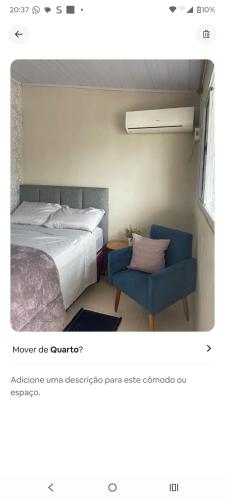 a bedroom with a bed and a blue chair at Condominio Central Charmoso in Uruguaiana