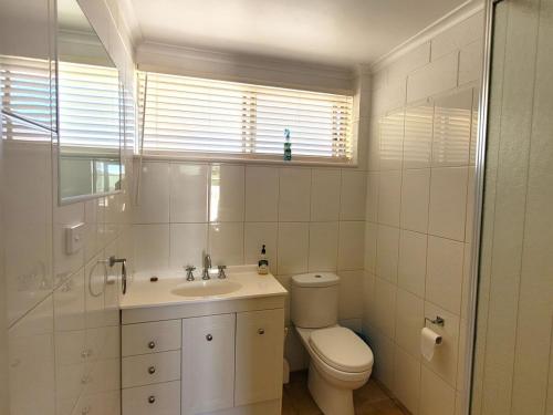 a white bathroom with a toilet and a sink at Baccarat in Port Vincent