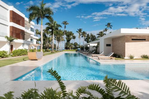 a swimming pool in front of a building with palm trees at Sol de Arena Beachfront Condos by Bocobay in Las Terrenas