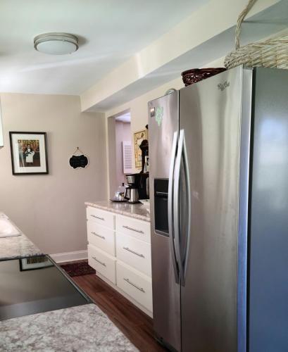 a kitchen with a stainless steel refrigerator and white cabinets at Virginia Country Cottage, GREAT Location, Pets in Troutville