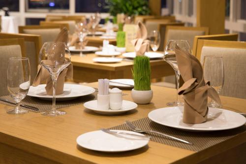a wooden table with white plates and glasses on it at Paradise Saigon Boutique Hotel & Spa in Ho Chi Minh City