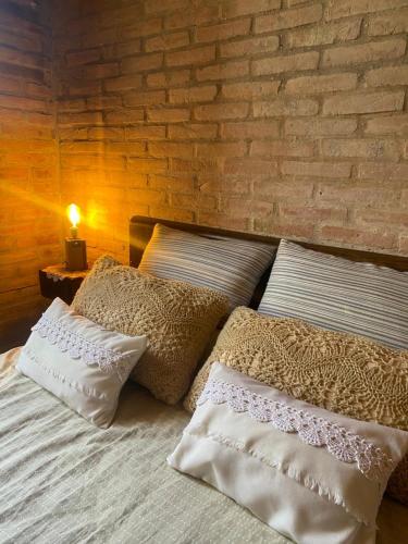 a bed with white pillows and a brick wall at Casas de Epoca -Serendipia in Charbonier