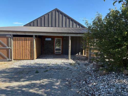 a brown barn with a door and a tree at River and Mountain Central in Queensberry