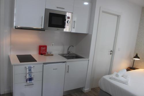 a small white kitchen with a sink and a microwave at Jardim da Trindade in Coimbra