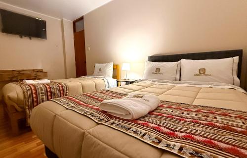 a hotel room with two beds with towels on it at Aruma Andina Hotel CHAVÍN in Chavín de Huantar