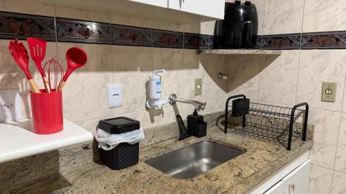 a kitchen counter with a sink and utensils at Amplo apartamento completo no Centro Cambuí in Campinas