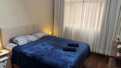 a bedroom with a blue bed with two pillows on it at Amplo apartamento completo no Centro Cambuí in Campinas